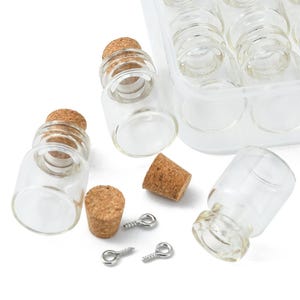 May include: Clear glass mini bottles with cork stoppers, displayed with a plastic container. The image also shows several loose corks and small silver eye pins. These small bottles are ideal for crafts or decorative purposes.