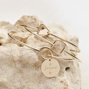 Può includere: Braccialetti rigidi in oro con forme geometriche e un ciondolo con il nome "Gaspard" inciso.