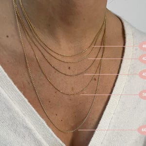 Puede incluir: Primer plano de una persona que lleva varias cadenas de oro, con medidas en cent&iacute;metros marcadas en la imagen. Las cadenas miden 40 cm, 42 cm, 45 cm, 50 cm y 60 cm de largo.