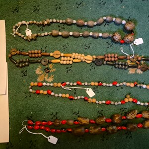 Könnte beinhalten: Vier Stränge Perlenketten mit verschiedenen Farben und Materialien. Die Ketten sind mit A, B, C und D beschriftet.