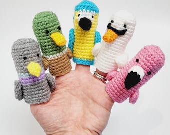 May include: Five colourful finger puppets, each with a different animal design. The puppets are made of crocheted yarn and feature a variety of colours, including green, blue, white, pink, and grey.