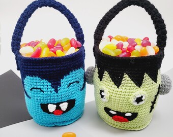 May include: Two handmade crochet Halloween treat buckets. One is blue with a monster face, the other is green with a Frankenstein face. Both are filled with colorful jelly beans and have matching handles. A few jelly beans are scattered in front.