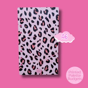 May include: A6-sized planner cover with a pink leopard print pattern. The cover features black and pink spots on a light pink background. The text "A6" is in a pink cloud, and the text "Printed Palette Budgets" is in a pink circle.