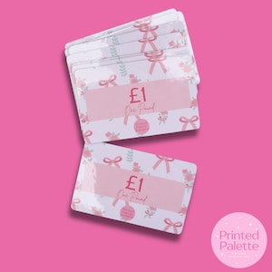 May include: A stack of gift cards with a floral and bow design. Each card displays "£1 One Pound" in text, with a pink section for writing. The cards are white with pink and green floral patterns and bows. The background is a solid pink.