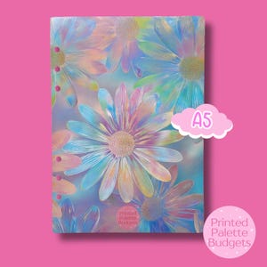 Peut inclure: Cahier A5 avec un motif floral. La couverture présente de grandes fleurs colorées dans les tons de bleu, rose, jaune et vert. Le texte "A5" est dans une bulle en forme de nuage. Le cahier est de "Printed Palette Budgets".