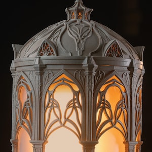 Puede incluir: Una linterna gris en forma de c&uacute;pula con intrincados detalles de celos&iacute;a arqueada que recuerdan a la mamposter&iacute;a arquitect&oacute;nica. La estructura est&aacute; iluminada desde el interior, proyectando un c&aacute;lido resplandor naranja a trav&eacute;s de las aberturas.