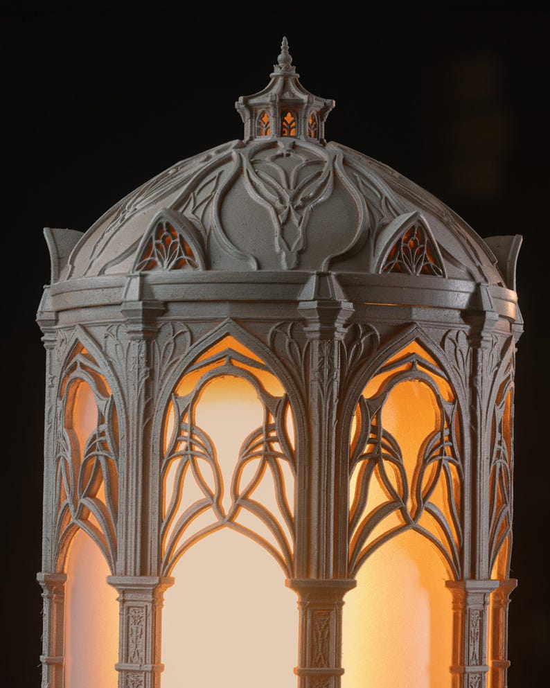 Puede incluir: Una linterna gris en forma de c&uacute;pula con intrincados detalles de celos&iacute;a arqueada que recuerdan a la mamposter&iacute;a arquitect&oacute;nica. La estructura est&aacute; iluminada desde el interior, proyectando un c&aacute;lido resplandor naranja a trav&eacute;s de las aberturas.