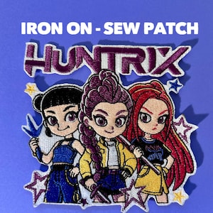 May include: An iron-on or sew patch featuring three stylized female characters with the text "HUNTRIX". The characters have black, purple, and red hair, and are wearing various outfits. The patch is outlined with white stitching and has star accents.