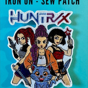May include: Embroidered patch featuring three female characters and a blue cat. The patch has the text "HUNT RX" and "IRON ON - SEW PATCH" in black. The characters are in various outfits and holding weapons.