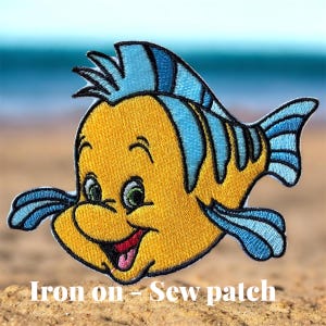 May include: Embroidered patch featuring a cartoon fish with a cheerful expression. The fish has yellow and blue coloring, with green eyes and a red mouth. The patch is designed to be ironed on or sewn onto fabric.