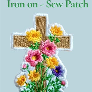 May include: Embroidered iron-on or sew-on patch featuring a cross shape with a floral design. The cross is tan with a white border, and the flowers are yellow, pink, and purple. The text "Iron on - Sew Patch" is above the cross.