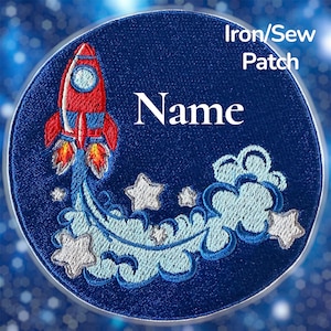 May include: Embroidered iron-on patch featuring a red rocket ship blasting off, surrounded by stars and clouds. The patch is circular, with the word "Name" in white and the text "Iron/Sew Patch". The background is a dark blue.