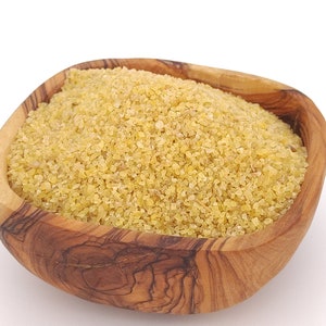 Pode incluir: Uma tigela de madeira cheia de bulgur cru.