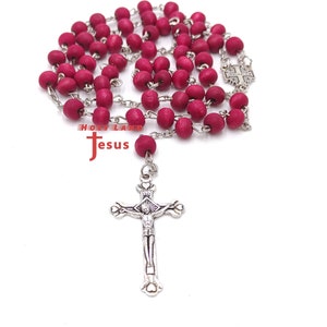 May include: A red wooden rosary with a silver crucifix. The crucifix features a depiction of Jesus Christ.
