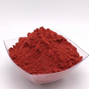 May include: A small, clear plastic bowl filled with a mound of bright red powder.