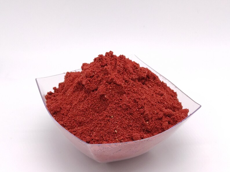 May include: A small, clear plastic bowl filled with a mound of bright red powder.
