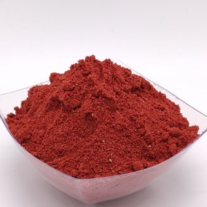 May include: A small, clear plastic bowl filled with a mound of bright red powder.