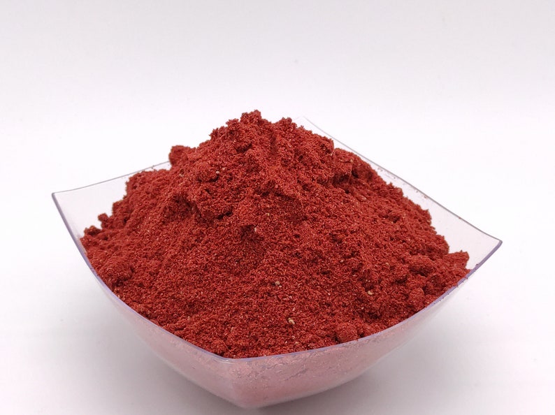 May include: A small, clear plastic bowl filled with a mound of bright red powder.