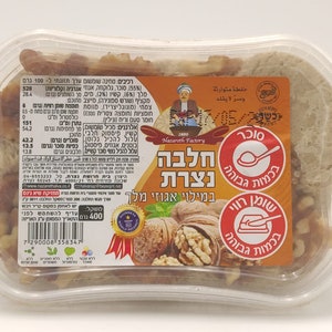 May include: A clear plastic container filled with halva, a Middle Eastern confection, and walnut pieces. The label features text in Hebrew and Arabic, along with images of walnuts and a spoon. The product weighs 400 grams.
