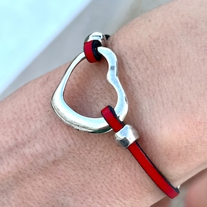 May include: A red leather bracelet with a silver heart-shaped clasp.