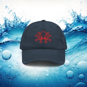 Könnte beinhalten: Eine blaue, abgenutzte Baseballkappe mit einem roten gestickten Kraken-Design.