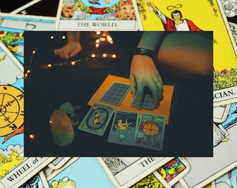 May include: A deck of tarot cards spread out on a dark surface with a small orange cloth. The cards feature illustrations including The World, The Magician, and The Wheel of Fortune. Several small, translucent crystals are placed nearby.