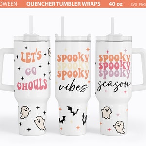 May include: Three white 40 ounce tumbler cups with different Halloween designs. The first cup has the text "Let's Go Ghouls" in a retro font with pink, orange, and yellow colors. The second cup has the text "Spooky Vibes" in a retro font with pink, orange, and yellow colors. The third cup has the text "Spooky Season" in a retro font with pink, orange, and yellow colors. All three cups have a white handle and a clear lid with a straw.