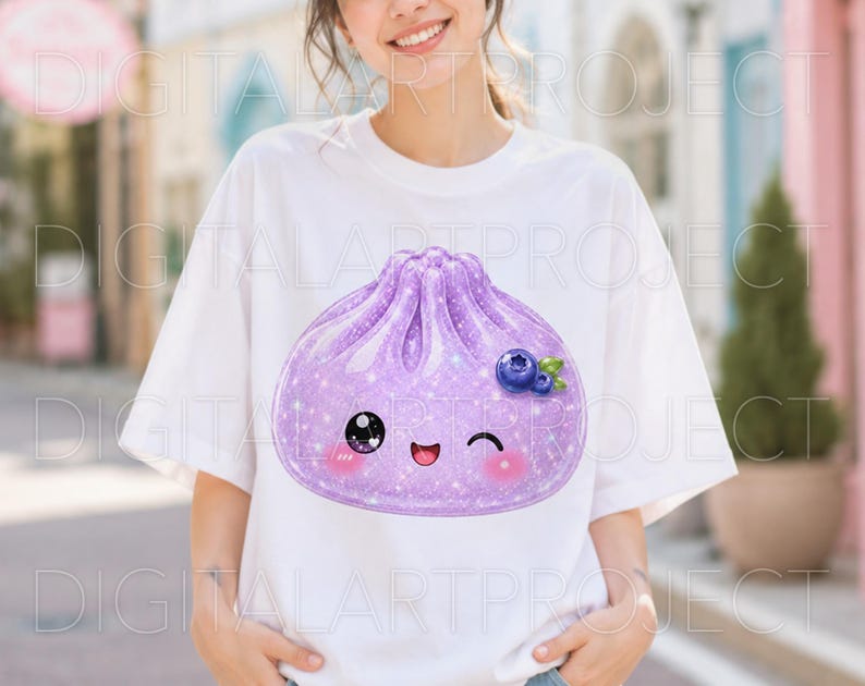 May include: A white short-sleeved t-shirt featuring a large, glittery purple dumpling graphic on the front. The dumpling has a cute, winking face with rosy cheeks and is decorated with a small cluster of blue blueberries and green leaves.