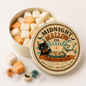 K&ouml;nnte beinhalten: Eine runde Metalldose gef&uuml;llt mit wei&szlig;en und orangefarbenen quadratischen Marshmallows. Der Deckel zeigt eine Grafik mit einer schwarzen Katze und einem Geist sowie den Text Midnight Mallow Co. Fluffy Sweets After Dark. Drei Bonbons liegen davor.
