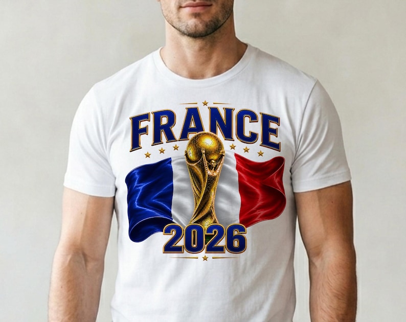 May include: White t-shirt featuring a graphic design with the word "FRANCE" in blue, gold stars, and the French flag. A gold trophy and the number "2026" are also displayed on the shirt.
