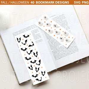 Puede incluir: Dos marcadores de libros con tem&aacute;tica de Halloween. Un marcador de libros presenta un fondo blanco con murci&eacute;lagos negros y estrellas naranjas. El otro marcador de libros presenta un fondo blanco con fantasmas grises y estrellas naranjas. Ambos marcadores de libros est&aacute;n en un libro.