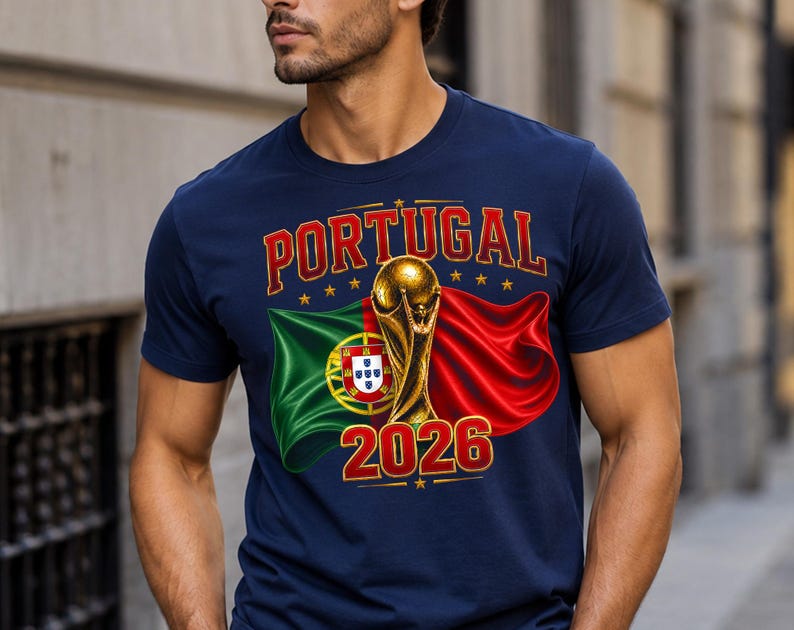 May include: Navy blue t-shirt featuring the word "PORTUGAL" in red and gold lettering, with a gold trophy and the year "2026". The design includes the Portuguese flag and a red flag.