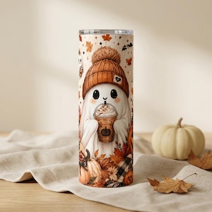 May include: A cylindrical tumbler featuring a white ghost character wearing a brown knit beanie and holding a plastic cup with a whipped cream topping. The design includes orange and brown autumn leaves, small pumpkins, and bats on a cream background.