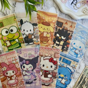 May include: A collection of clear plastic budget envelopes featuring various cartoon characters in cafe settings. Each envelope has a different character, including a frog, dog, bear, and cat, holding a notepad. The envelopes are arranged on a marble surface.