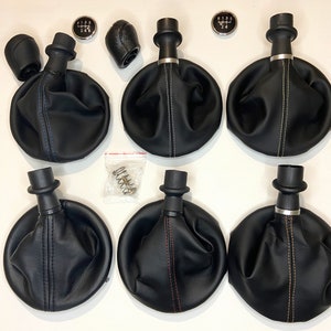 May include: Six black leather gear shift knobs with different coloured stitching. The knobs have a silver metal ring around the base. Each knob is paired with a silver gear shift pattern.