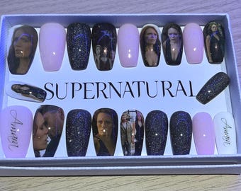 May include: A set of press-on nails featuring images of characters from the TV show "Supernatural." The nails are in various colors, including pink and black glitter, with the word "Supernatural" printed on the box.