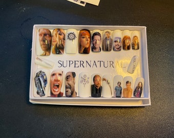 May include: A set of 16 Supernatural themed press-on nails featuring images of the main characters, the Impala car, and symbols from the show. The nails are packaged in a white box with the word "Supernatural" printed on the front.