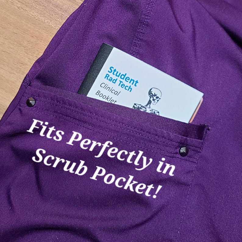 Op de afbeelding: Een paarse scrubzak met een witte tekstoverlay die "Fits Perfectly in Scrub Pocket!" luidt. Een klein wit boekje met de tekst "Student Rad Tech Clinical Booklet" zit in de zak.