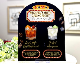 May include: A black casino-themed sign with the text "MICHAEL'S 60TH CASINO NIGHT Signature Drinks." It features illustrations of two cocktails: a High Roller Old-Fashioned and a Jackpot Margarita, with their ingredients listed below.