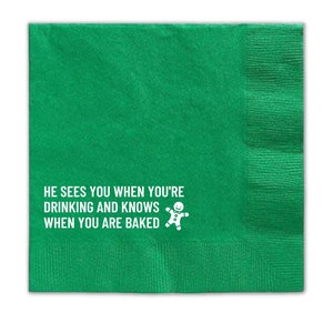 Op de afbeelding: Groene papieren servet met de tekst "He sees you when you're drinking and knows when you are baked" en een afbeelding van een peperkoekman.