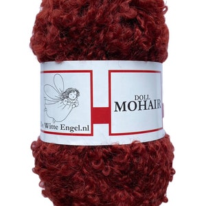May include: A ball of dark red doll mohair yarn. The yarn has a curly, textured appearance. A white label with red accents wraps around the yarn, displaying the text "DOLL MOHAIR" and a logo of a fairy. The website "De Witte Engel.nl" is also printed on the label.