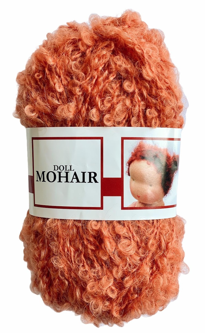 May include: A ball of peach-colored doll mohair yarn. The yarn is tightly curled and has a soft, fuzzy texture. A white label wrapped around the yarn reads "DOLL MOHAIR" with a doll's face on the right side.