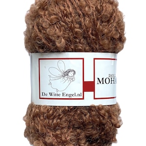 May include: A ball of brown mohair yarn with a curly texture. The yarn is wrapped with a white label featuring a fairy illustration and the text "De Witte Engel.nl" and "DOLL MOHAIR". The yarn is suitable for knitting and crochet projects.