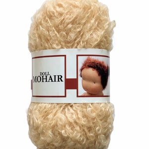 May include: A ball of light beige doll mohair yarn. The yarn is tightly curled and has a soft, fluffy texture. A label wrapped around the yarn reads "DOLL MOHAIR" and features an image of a doll's face.
