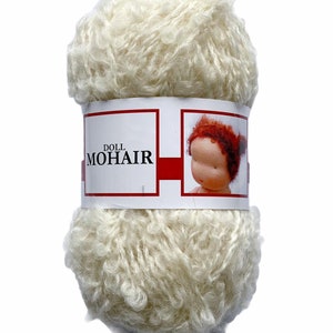 May include: A skein of off-white doll mohair yarn. The yarn is tightly wound and has a fluffy, textured appearance. A label wrapped around the yarn displays the text "DOLL MOHAIR" and a picture of a doll with red hair.