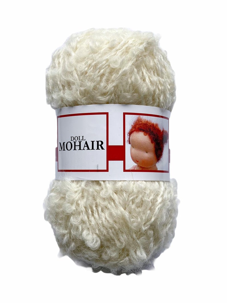 May include: A skein of off-white doll mohair yarn. The yarn is tightly wound and has a fluffy, textured appearance. A label wrapped around the yarn displays the text "DOLL MOHAIR" and a picture of a doll with red hair.