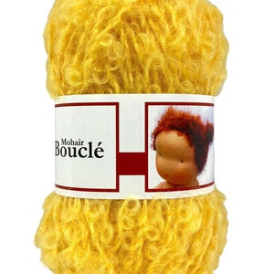 May include: A skein of bright yellow Mohair Boucl&eacute; yarn. The yarn is tightly wound and has a curly, textured appearance. The label features the text "Mohair Boucl&eacute;" and an illustration of a doll.