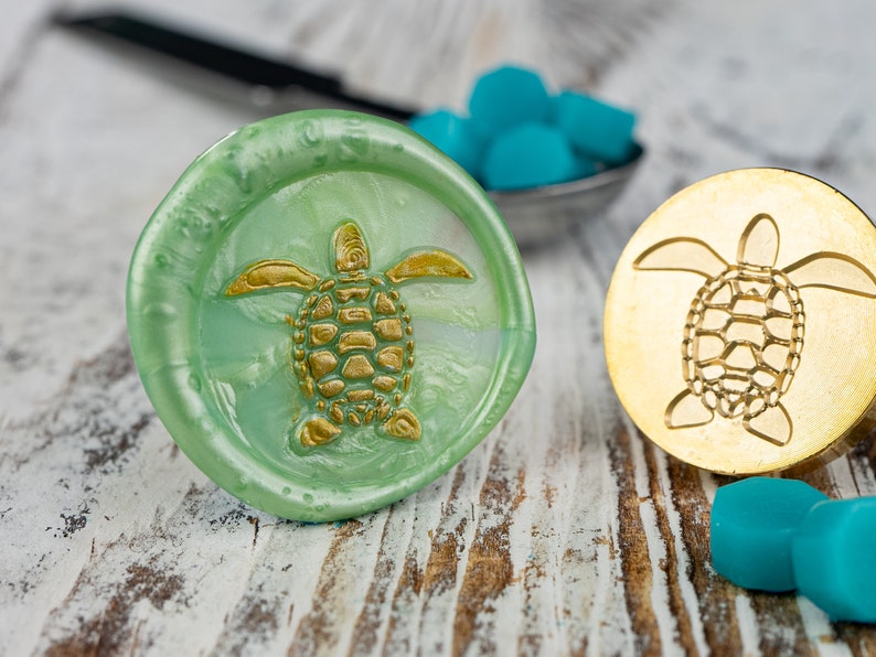 May include: Two wax seals with a turtle design. One seal is green with a gold turtle, the other is gold with a gold turtle.