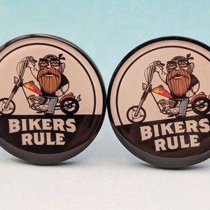 May include: A pair of black and white round buttons with a cartoon image of a bearded man riding a motorcycle. The text "Bikers Rule" is printed on the buttons.