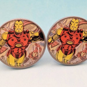 May include: A pair of round, silver-colored, iron man themed, comic book character, cufflinks. The cufflinks feature a red and yellow iron man character on a background of comic book panels.